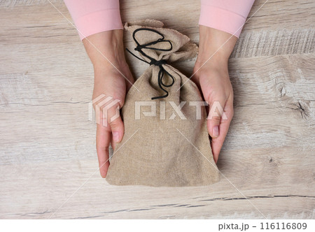 Female hands holding a stuffed canvas bag, concept of wealth and success Female hands holding a stuffed canvas bag, concept of wealth and success 116116809
