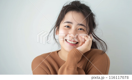 頬に手を当ててにっこりと微笑む若い日本人女性のポートレート 116117078