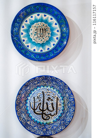 blue traditional Asian Uzbek ceramic plates hand-painted on white wall at a souvenir tableware shop in Uzbekistan 116117157