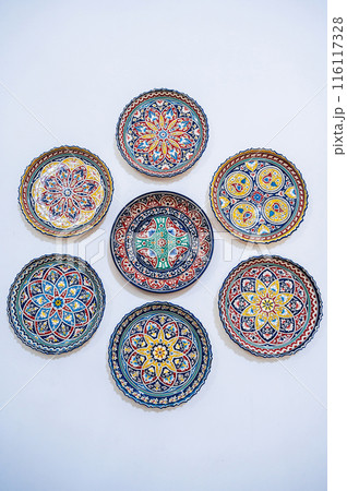 traditional Uzbek ceramic plates hand-painted on white wall at oriental souvenir tableware shop in Uzbekistan traditional Uzbek ceramic plates hand-painted on white wall at oriental souvenir tableware shop in Uzbekistan 116117328