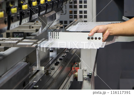 Close up the bending machine operator hold the sheet metal parts. Close up the bending machine operator hold the sheet metal parts. 116117391