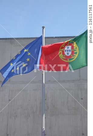 Portuguese and European Union flags waving against a building 116117561