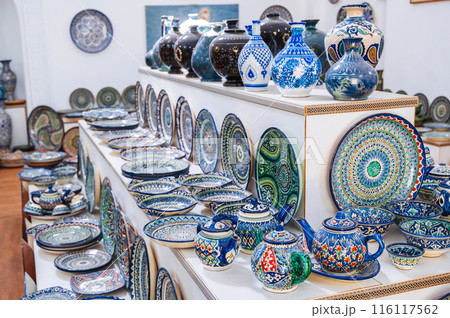 Uzbek handmade ceramic plates and tableware with hand-painted traditional Asian colorful patterns in souvenir store 116117562