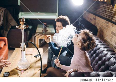 beautiful blond woman smoking while sitting with friends 116117587