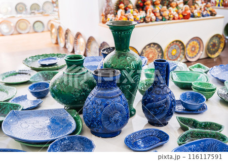 Uzbek handmade ceramic plates, vases and jug with hand-painted traditional Asian patterns in pottery workshop 116117591