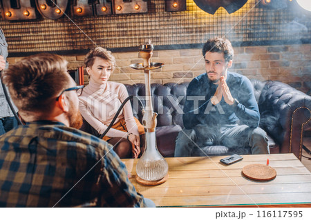 A young pensive company of people is smoking a hookah 116117595
