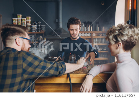 young stylsh man taking a glass from barmen 116117657