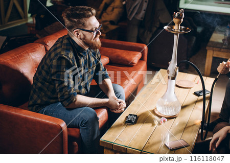 cherful ginger man in stylish clothes sitting on the sofa 116118047
