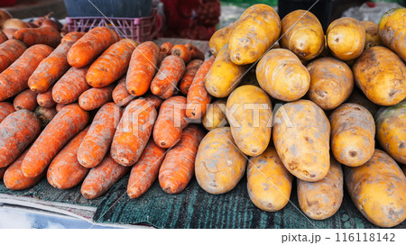 fresh harvest of orange and yellow carrots on shelves of vegetable farmers bazaar 116118142