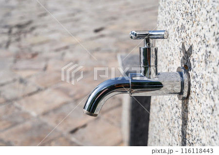 modern metal outdoor faucet with clean drinking water in park on street in the city in summer close-up modern metal outdoor faucet with clean drinking water in park on street in the city in summer close-up 116118443