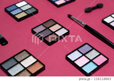 A set of multi-colored eyeshadow and brushes on a pink background. Eye makeup A set of multi-colored eyeshadow and brushes on a pink background. Eye makeup 116118663