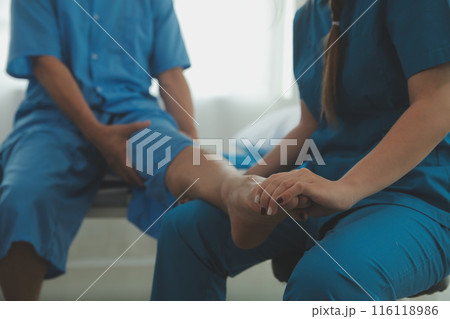 Physical therapists work with patients in close-up clinics. The concept of rehabilitation of physical health, the doctor gives advice to the patient. Ankle problems and muscle injuries Physical therapists work with patients in close-up clinics. The concept of rehabilitation of physical health, the doctor gives advice to the patient. Ankle problems and muscle injuries 116118986