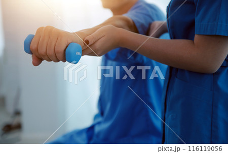 Physiotherapist man giving exercise with dumbbell treatment About Arm and Shoulder of athlete male patient Physical therapy concept 116119056