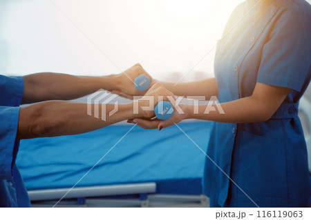 Physiotherapist man giving exercise with dumbbell treatment About Arm and Shoulder of athlete male patient Physical therapy concept 116119063