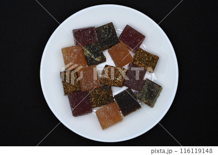 Multicolored marmalade on a white plate. Sweets on a black background. 116119148
