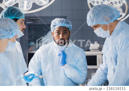 Indian surgeon looking extremely shocked during surgical operation 116119151