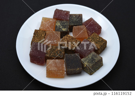 Multicolored marmalade on a white plate. Sweets on a black background. 116119152