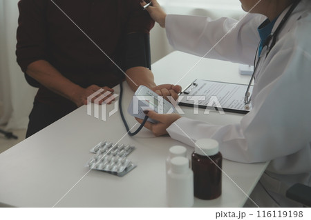Doctor using sphygmomanometer with stethoscope checking blood pressure to a patient in the hospital. Doctor using sphygmomanometer with stethoscope checking blood pressure to a patient in the hospital. 116119198
