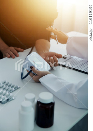 Doctor using sphygmomanometer with stethoscope checking blood pressure to a patient in the hospital. Doctor using sphygmomanometer with stethoscope checking blood pressure to a patient in the hospital. 116119199