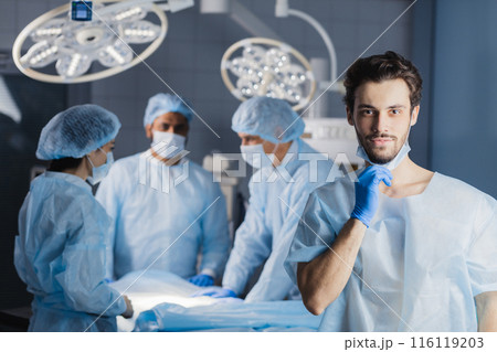 Surgeon looking at camera with colleagues Surgeon looking at camera with colleagues 116119203