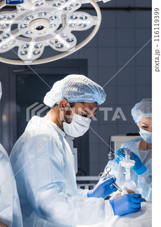 Medical Team Performing Surgical Operation in Bright Modern Operating Room Medical Team Performing Surgical Operation in Bright Modern Operating Room 116119399