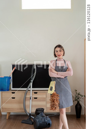 Housekeeper Standing with Cleaning Supplies in Modern Living Room Ready for Housework 116120128