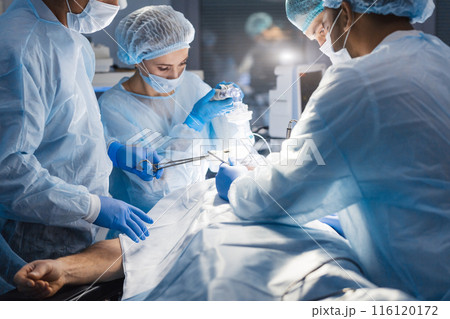 Diverse Team of surgeon, assistants and nurses making invasive surgery 116120172