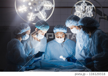 Doctors team in surgery in a dark background Doctors team in surgery in a dark background 116120318