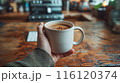 Closeup Of Hand Holding Coffee Mug On Wooden Table In Cafe 116120374