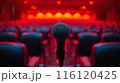 A Single Microphone on a Stage With Red Lights and Empty Seats 116120425