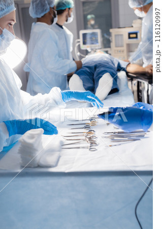Surgical tools lying on table with nurse near and surgeons at background. 116120997