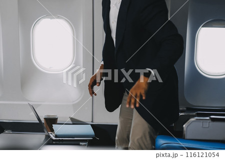 man putting luggage on the top shelf on airplane man putting luggage on the top shelf on airplane 116121054