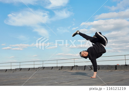 Asian hip-hop man dancer making a backdancing stunts outdoor on the roof 116121219