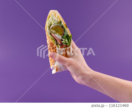 female hand holding an appetizing doner on a pink background for a food delivery site 1 116121460