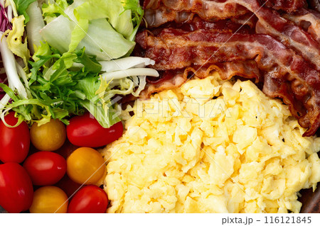 Breakfast plate . Scrambled eggs , bacon , cherry tomatoes and salad 116121845