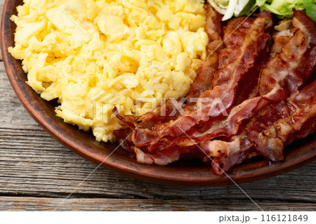 Breakfast plate . Scrambled eggs , bacon , cherry tomatoes and salad 116121849