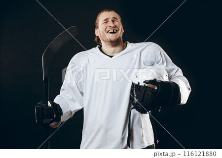 Handsome hockey player. Smiling at camera isolated on black background. 116121880