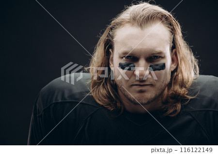 Determined American football player posing with painted face and chewing gum 116122149