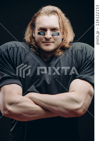 Determined American football player posing with painted face and chewing gum 116122153
