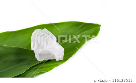 White crystal clear alum cube on green leaf isolated on white background. White crystal clear alum cube on green leaf isolated on white background. 116122513