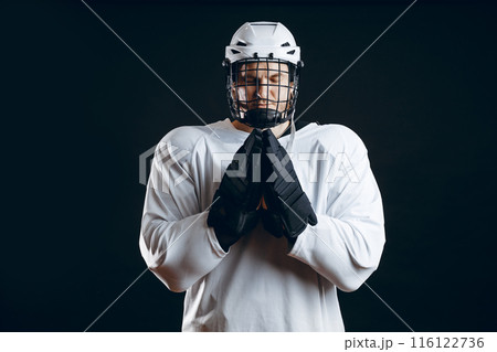 Caucasian hockey player, in uniform, isolated on black, prays for good luck. Caucasian hockey player, in uniform, isolated on black, prays for good luck. 116122736