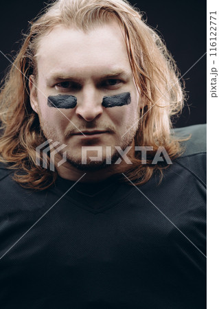 Determined American football player posing with painted face and chewing gum 116122771