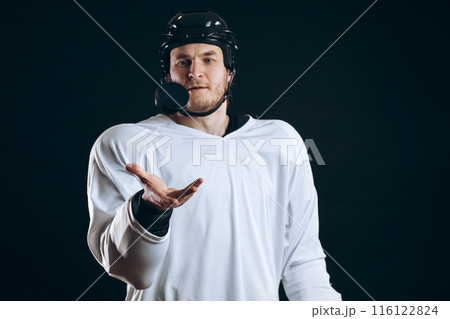 Hockey player bites the puck with broken teeth and looking at camera with a grin. 116122824