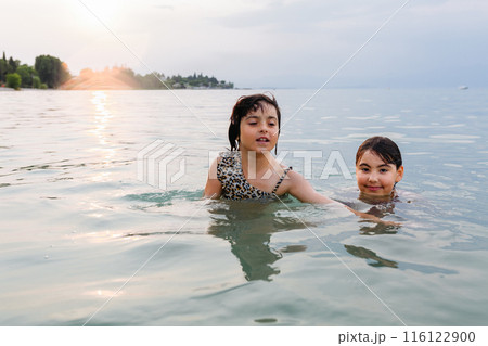two children swimming in the lake in the evening two children swimming in the lake in the evening 116122900