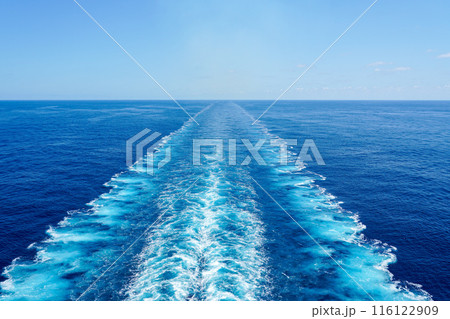 Wide turbulent white foam water trail behind a large cruise ship in a calm blue sea on a sunny day Wide turbulent white foam water trail behind a large cruise ship in a calm blue sea on a sunny day 116122909