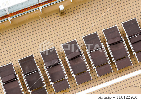 A fragment of the plank deck of a luxury cruise ship with brown sun loungers in a row, no people A fragment of the plank deck of a luxury cruise ship with brown sun loungers in a row, no people 116122910