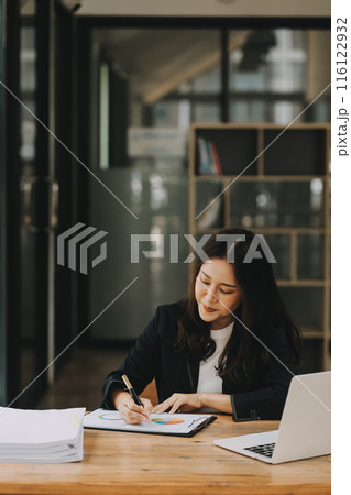 Cheerful business lady working on laptop in office, Asian happy beautiful businesswoman in formal suit work in workplace. Attractive female employee office worker smile. Cheerful business lady working on laptop in office, Asian happy beautiful businesswoman in formal suit work in workplace. Attractive female employee office worker smile. 116122932