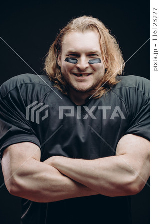 Determined American football player posing with painted face and chewing gum Determined American football player posing with painted face and chewing gum 116123227