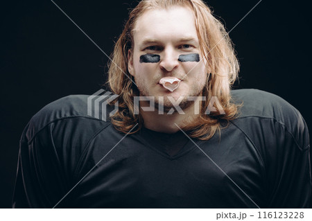 Determined American football player posing with painted face and chewing gum Determined American football player posing with painted face and chewing gum 116123228