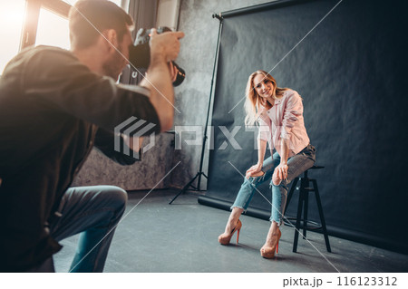 smiling positive model in fashion clothes sitting on the chair 116123312